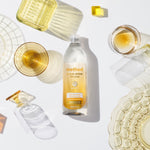 Styled overhead scene with Method Super Shine dish soap bottle surrounded by glassware and soft shadows on white