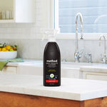 Method Daily Granite Cleaner bottle placed on a marble kitchen countertop with sink and faucet in the background.