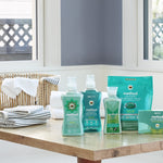 Lifestyle scene of Method laundry products including beach sage detergent, softener, booster and dryer sheets on a wooden table