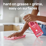 Person wiping a countertop while holding a method pink grapefruit spray bottle, headline about grease and grime visible