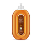 Clear oval bottle of Method Squirt + Mop wood floor cleaner with almond-scent label and amber liquid