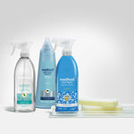 Staged group of Method cleaning products including spray and bottle variants arranged with sponges on a tray
