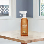 Method Daily Wood Cleaner bottle placed on a light wood table in a bright kitchen setting with windows behind