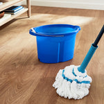 Lifestyle scene of a microfiber twist mop and blue plastic bucket on a wood-look floor near shelving