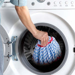 Hand placing blue-and-white twisted microfiber mop refill into front-loading washing machine drum