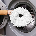 Hand holding a white microfiber mop refill at the opening of a front-load washing machine drum.