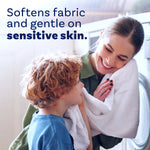 Woman and child smiling while holding a soft white towel with headline text about softening fabric and being gentle on sensitive skin