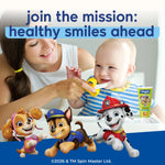 Smiling mother feeding a baby with a training toothbrush; PAW Patrol characters and Orajel tube overlay at bottom