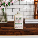 Mrs. Meyer’s Baking Soda Cream Cleaner bottle styled on a wooden countertop with subway tile backsplash and decorative items