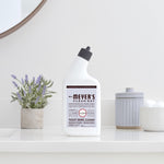 Styled bathroom scene with a bottle of Mrs. Meyer's lavender toilet bowl cleaner on a vanity beside a small plant