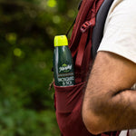 Murphy's Naturals mosquito & tick repellent can tucked into the side pocket of a red backpack worn outdoors