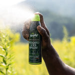 Hand holding and spraying a Murphy's Naturals lemon eucalyptus mosquito & tick repellent can outdoors with mist visible