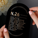 Hands holding a black informational card titled N.26 with descriptive copy about the perfumers and laundry scent experience
