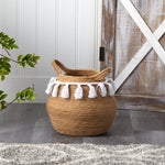 Nearly Natural jute tassel basket planter styled on floor next to barn-style door and greenery in a home setting