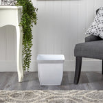Nearly Natural white fluted metal square planter styled on a floor between a side table and chair in a room setting