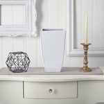 White tapered square metal planter styled on a console table with decorative candleholder and geometric accent.