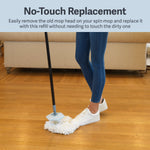 Person using a foot to remove or attach a white microfiber spin mop head on hardwood floor