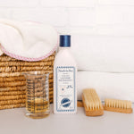 Noodle & Boo laundry detergent bottle styled with measuring cup, brushes and woven basket
