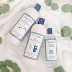 Three Noodle & Boo laundry products on a soft white towel, center Ultra-Soft Fabric Conditioner visible