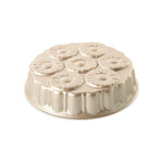 Gold-toned metal cake pan with seven pineapple-style ring molds arranged in a circular pattern