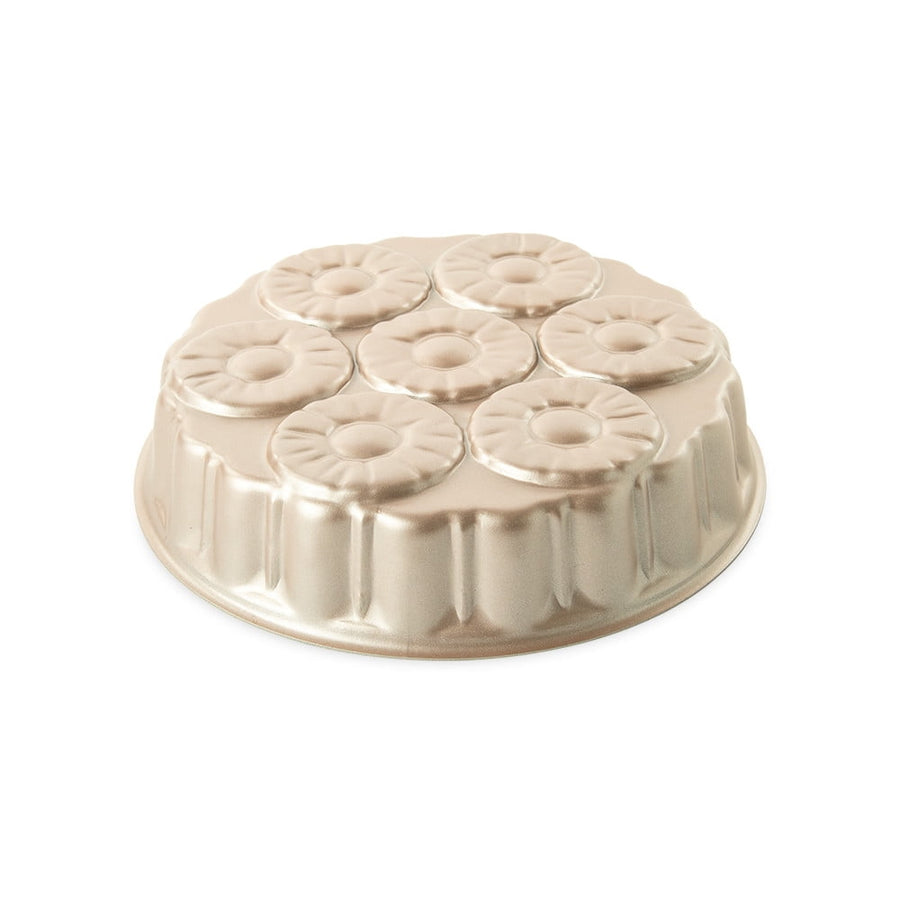 Gold-toned metal cake pan with seven pineapple-style ring molds arranged in a circular pattern