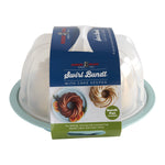 Nordic Ware cake keeper packaging showing clear dome lid over teal base with branded paper sleeve and bundt pan image