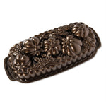 Bronze-toned decorative loaf pan with raised pumpkins and wheat motif, angled on white background