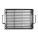 Overhead studio shot of aluminum roasting pan with black crisping rack and handles on white background