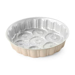 Shallow round metal cake pan with fluted outer edge and seven pineapple-style impressions visible on the interior surface