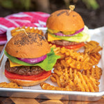 Aluminum quarter sheet pan used as a serving tray with two burgers and waffle fries on a picnic-style background.