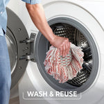Hand placing an O-Cedar white-and-red spin mop head into the drum of a front-loading washing machine with wash & reuse text