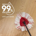 O-Cedar triangular mop head attached to a rod on a wood floor with text stating it removes 99% bacteria with just water