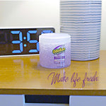 Small OdoBan OdoMagnet lavender gel crystal jar on a bedside table beside an alarm clock and decorative vase