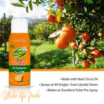 OdoBan Real Citrus air freshener can placed against a sunlit orchard scene with ripe oranges on branches in the background.