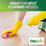 Gloved hands using a pink cloth and spraying OdoBan Luxury Vinyl cleaner on a wood-look floor with brand logo