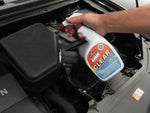 Hand holding an Oil Eater Cleaner Degreaser spray bottle while spraying over a car engine bay