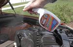 Spray bottle of Oil Eater Cleaner Degreaser being sprayed over a vehicle engine, visible spray mist from the nozzle