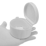 Open white plastic retainer case with visible internal strainer held on a gloved hand against white background.
