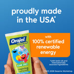 Blue background graphic stating 'proudly made in the USA' with a hand holding an Orajel Naturals Sesame Street toothpaste tube