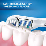 Illustration of an Oral‑B toothbrush head cleaning along teeth with copy 'SOFT BRISTLES GENTLY SWEEP AWAY PLAQUE' on blue background