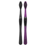 Two Oral‑B manual toothbrushes displayed upright, one black charcoal and one purple, showing full handles and heads.