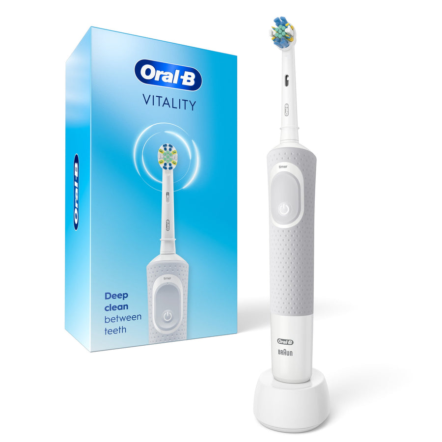 Oral‑B Vitality white rechargeable electric toothbrush standing on its charging base next to product box.