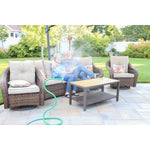 Green Orbit Cobra misting hose spraying fine mist beside a wicker patio seating area with people