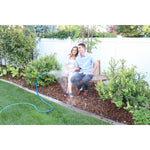 Blue flexible Orbit Cobra misting hose spraying mist toward a couple seated on a garden bench