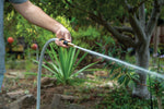 Lifestyle photo of a person using a brass adjustable nozzle to water plants in a garden