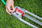 Close-up of an Orbit oscillating sprinkler laid on grass with a hand adjusting the red control