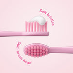 Close-up of two pink toothbrush heads showing soft bristles and slim brush head with curved text highlighting features.