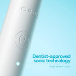 Close-up macro of Ordo toothbrush body showing embossed logo, power button and LED indicator on pale blue background