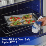 Oven scene showing a parchment-lined baking pan with small flatbread pizzas being placed into the oven using a kitchen towel.
