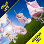Pink baby hat, shoe, mitten and plush toy hanging on a clothesline against sky with bold "color safe" and "chlorine free" banners.